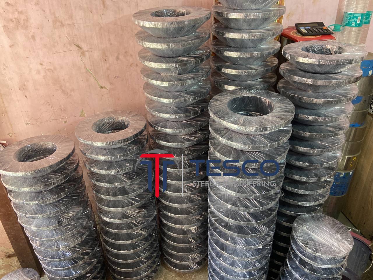 ASTM A105 carbon steel flanges bulk-stacked and plastic-wrapped in tall columns ready for export dispatch — carbon steel pipe flanges manufacturer Mumbai India