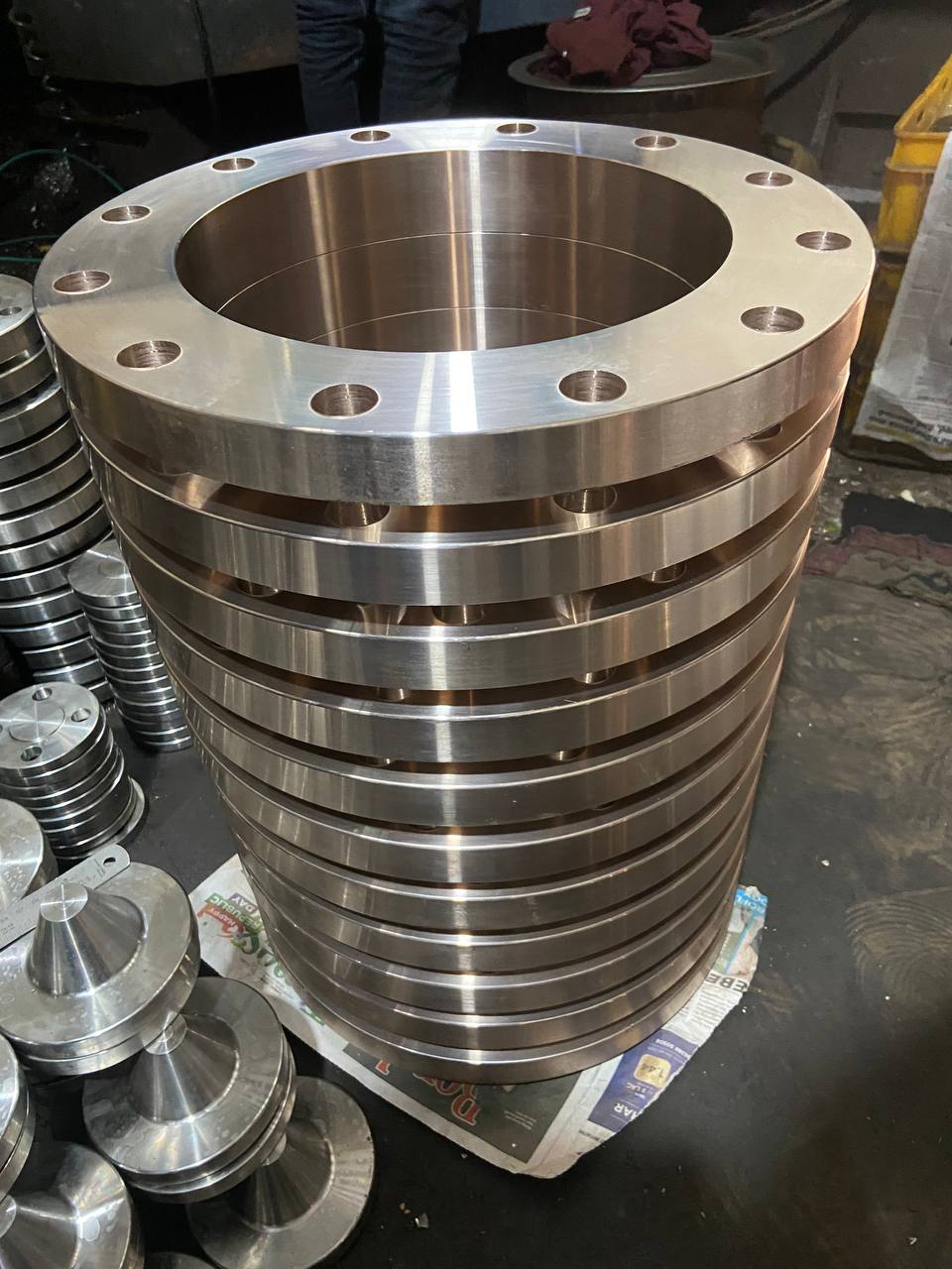 Stack of machined Copper Nickel 90/10 weld neck flanges ready for final inspection before export packaging