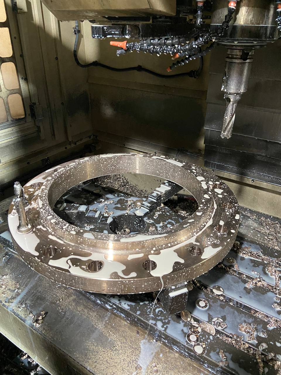 CNC milling of large Copper Nickel flange on vertical machining centre with coolant flood during manufacturing process