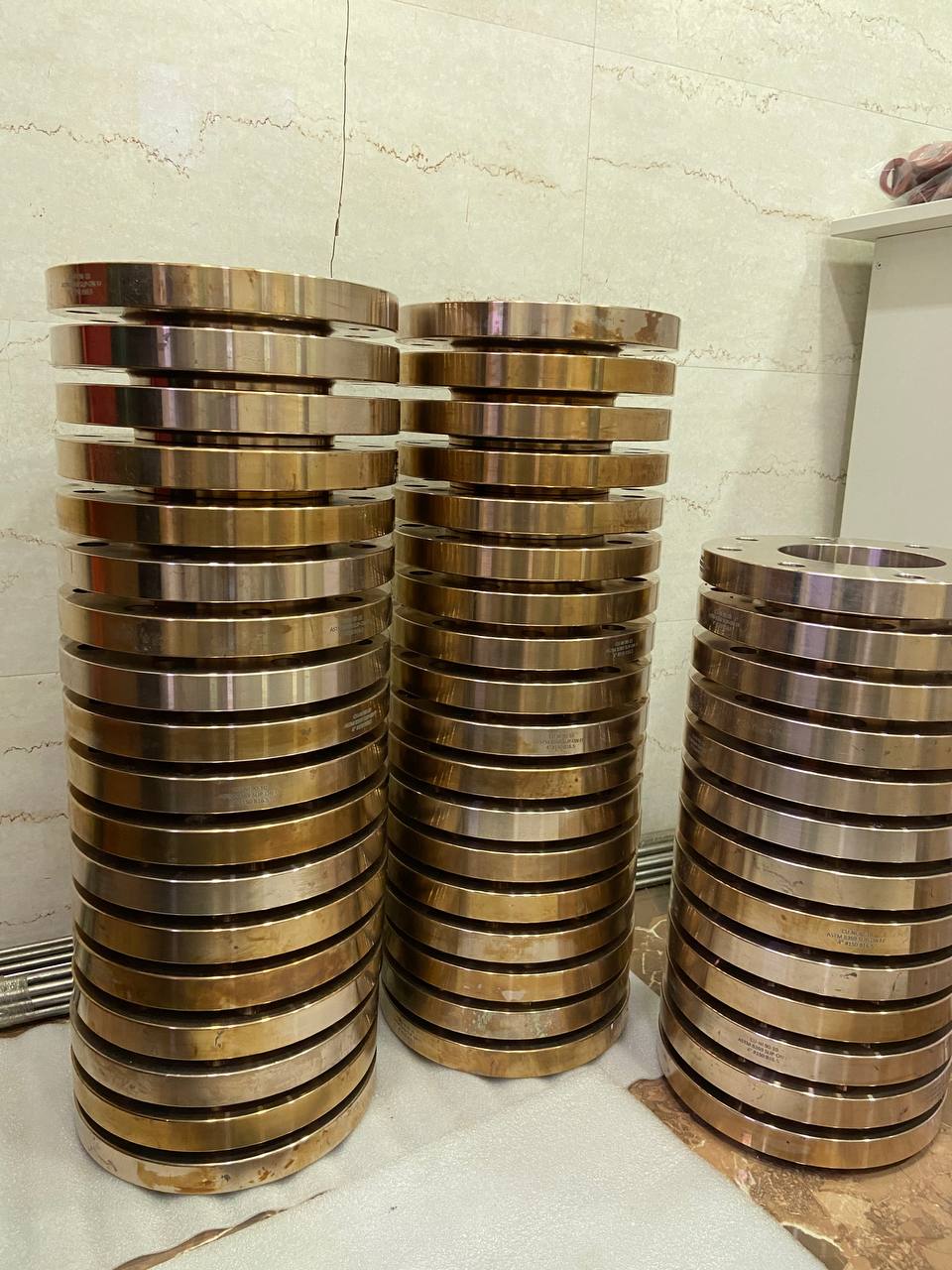 Bulk stock of Copper Nickel 90/10 slip-on flanges stacked in three columns awaiting export dispatch