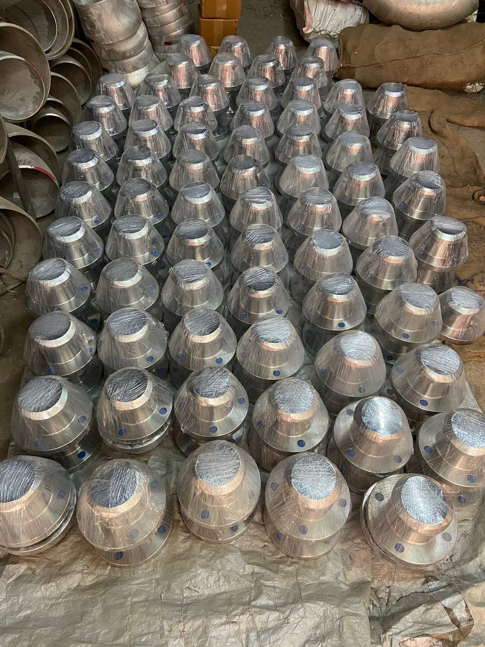 Hundreds of duplex steel weld neck flanges plastic-wrapped and laid out in warehouse before bulk export — ASTM A182 F51 F60, Tesco Steel & Engineering India
