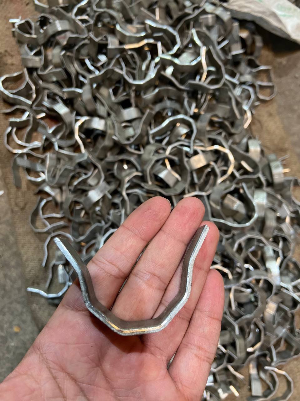 Flat V refractory anchor sample held in hand over production batch