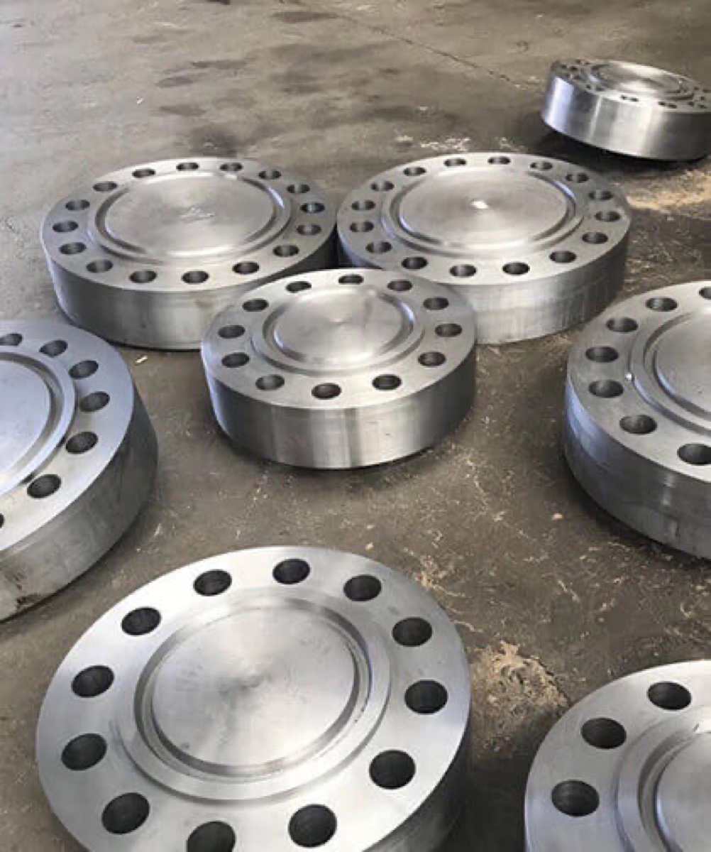 Machined alloy blind flanges with recessed faces laid out on the shop floor