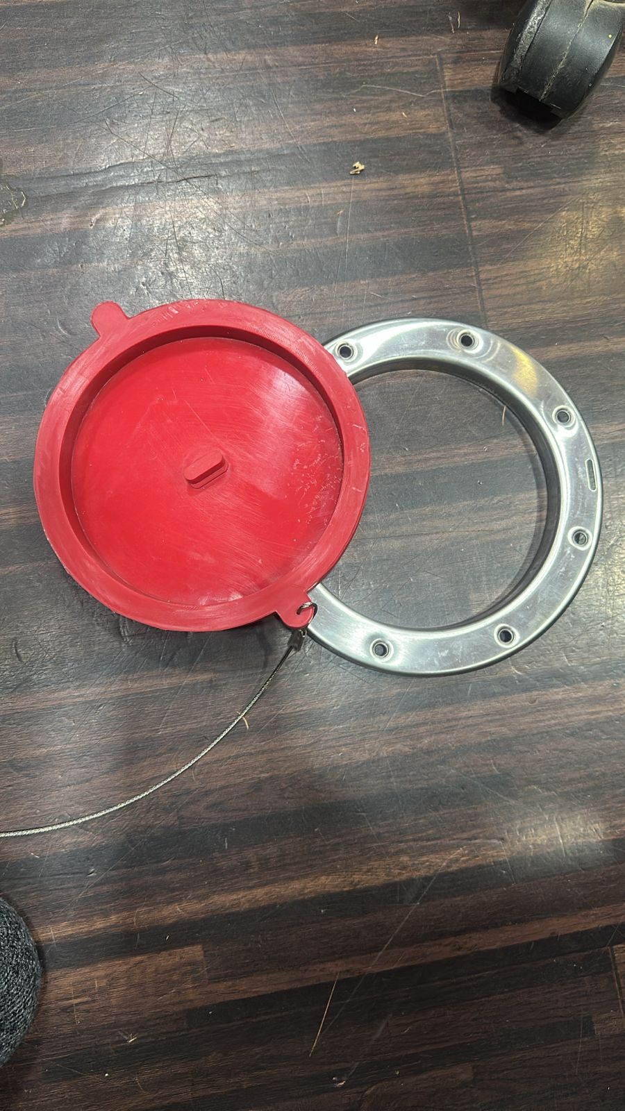 Red industrial-grade silicone inspection plug with convex sealing base beside SS304 stainless steel flange ring with fixing holes