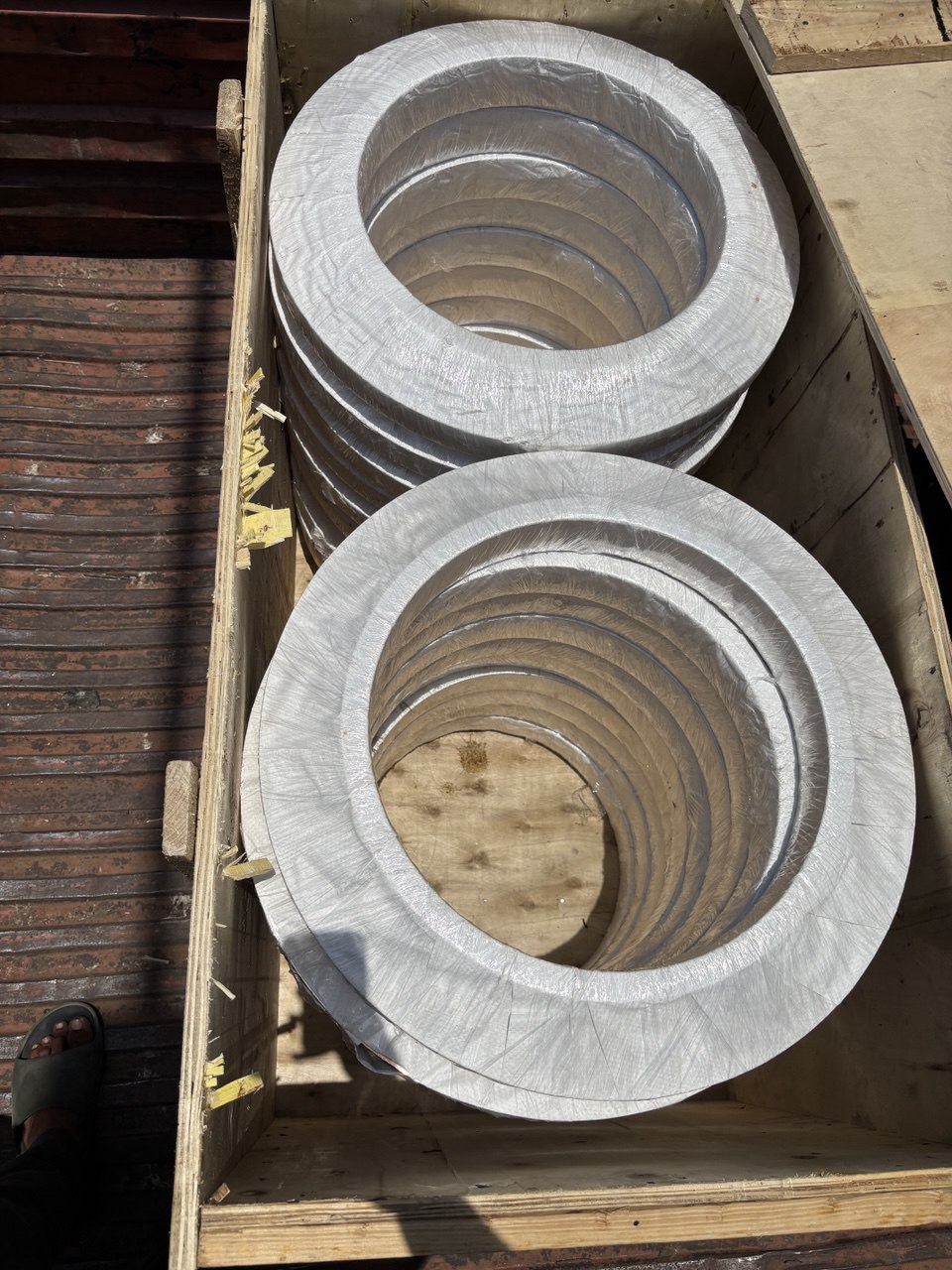 Large diameter stainless steel weld neck flanges stacked and plastic-wrapped in wooden export box — Tesco Steel & Engineering India