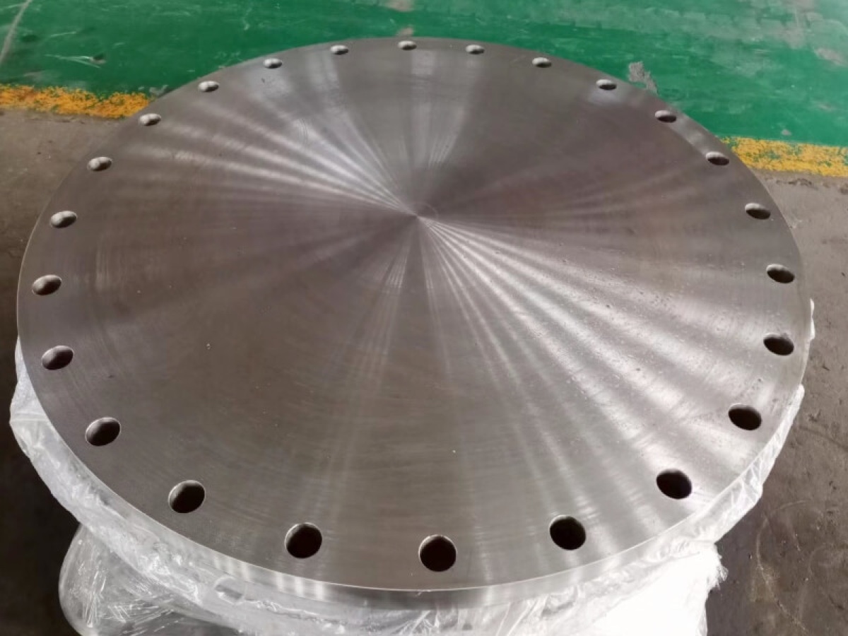 Large machined steel blind flange with bright spiral face finish on protective wrapping
